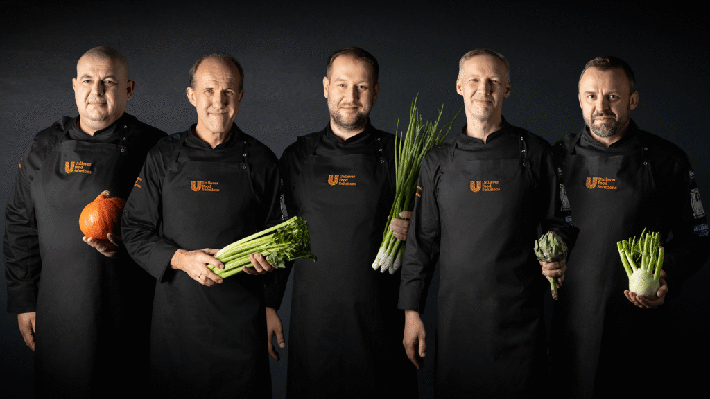Pięciu szefów kuchni UFS – stoją w czarnych fartuchach na czarnym tle, każdy trzyma w dłoniach jakieś warzywo